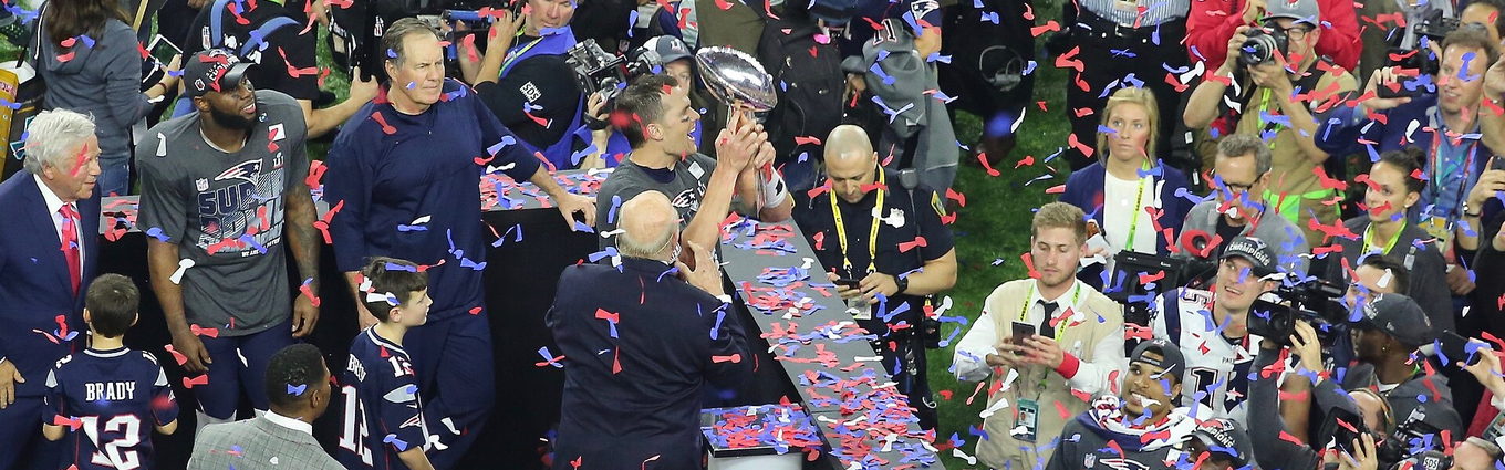 Confetti falling over the postgame podium as the Vince Lombardi Trophy is passed in front of a crowd of photographers