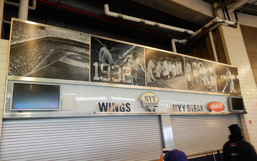 A shuttered concession counter on a stadium concourse beneath a historical photo mural