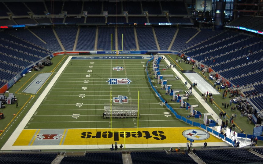 An empty stadium bowl with a few figures on the field and STEELERS lettering in the end zone