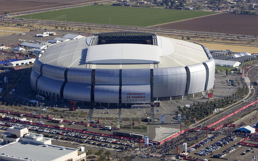 A domed stadium from the air, ringed by parking lots and farmland